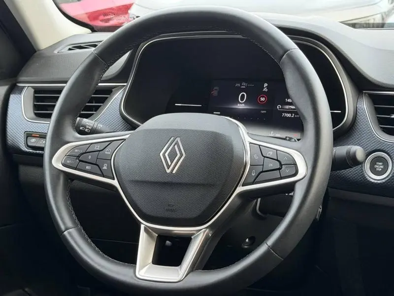 Vue rapprochée du volant noir de la Renault Arkana 2025 avec tableau de bord digital et bouton start/stop visible.