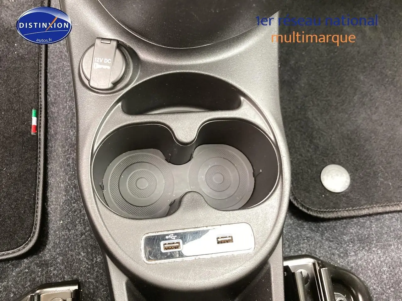 Gros plan sur la console centrale de la Fiat 500 gris avec porte-gobelets et prises USB visibles.