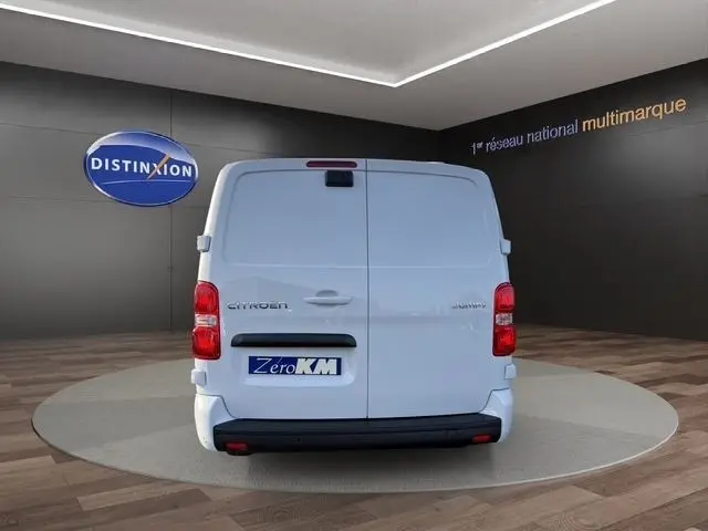 Vue arrière d'un Citroën Jumpy XL blanc, portes battantes fermées, sur fond intérieur avec logo Distinxion.