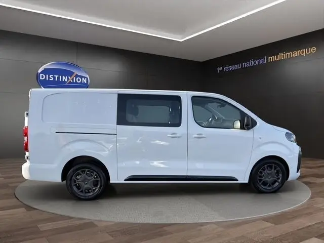 Vue latérale droite d’un Citroën Jumpy XL blanc, fourgon utilitaire avec vitres latérales et jantes foncées.