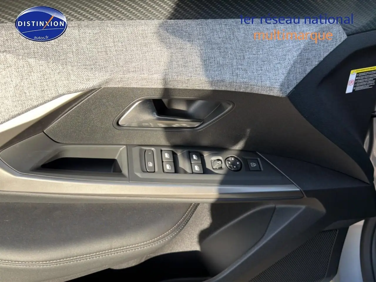 Vue intérieure côté gauche de la porte avant du Peugeot 5008 gris Artense avec commandes des vitres et rétroviseurs.