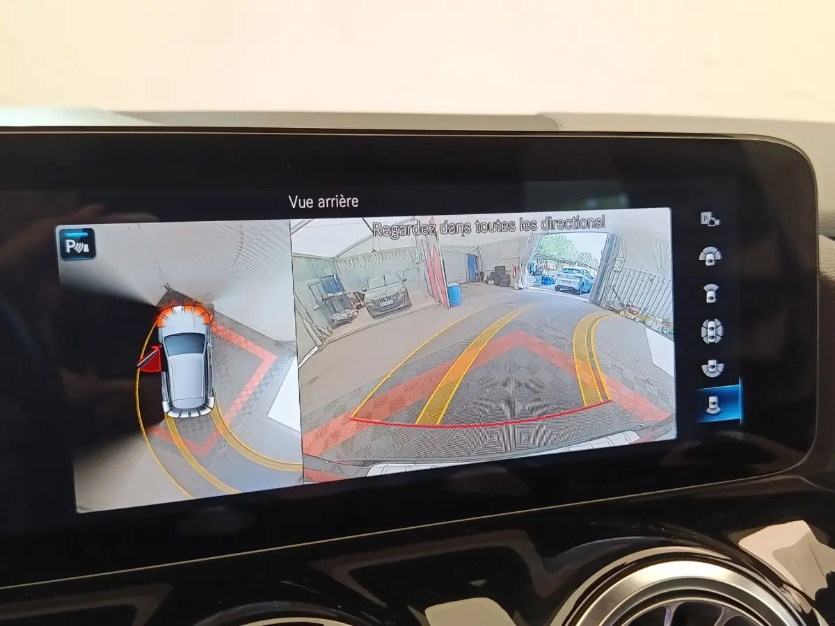Écran multimédia montrant la caméra de recul et vue 360° du Mercedes GLA 250 e AMG Line noir en stationnement.