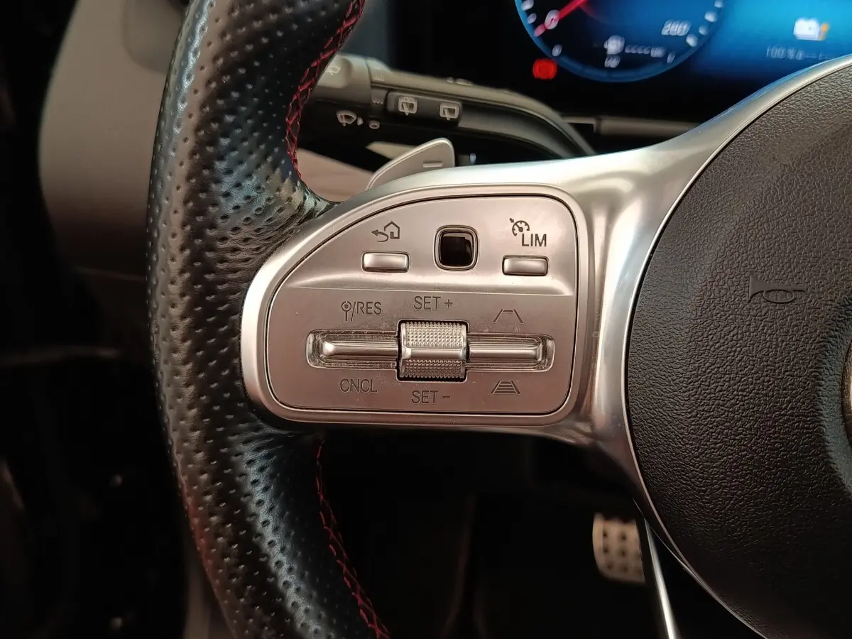 Gros plan sur le côté gauche du volant cuir perforé noir avec commandes de régulateur de vitesse du Mercedes GLA 250 e AMG Line 2021.