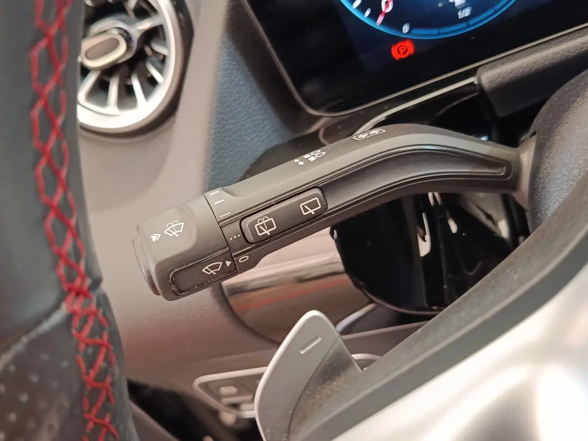 Gros plan sur la commande d’essuie-glace à gauche du volant cuir noir avec surpiqûres rouges du Mercedes GLA 250 e AMG LINE.