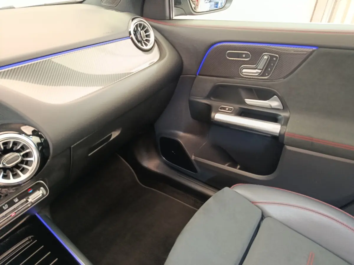 Intérieur côté passager d'une Mercedes GLA 250 e AMG Line 2021, avec éclairage d'ambiance bleu et surpiqûres rouges.