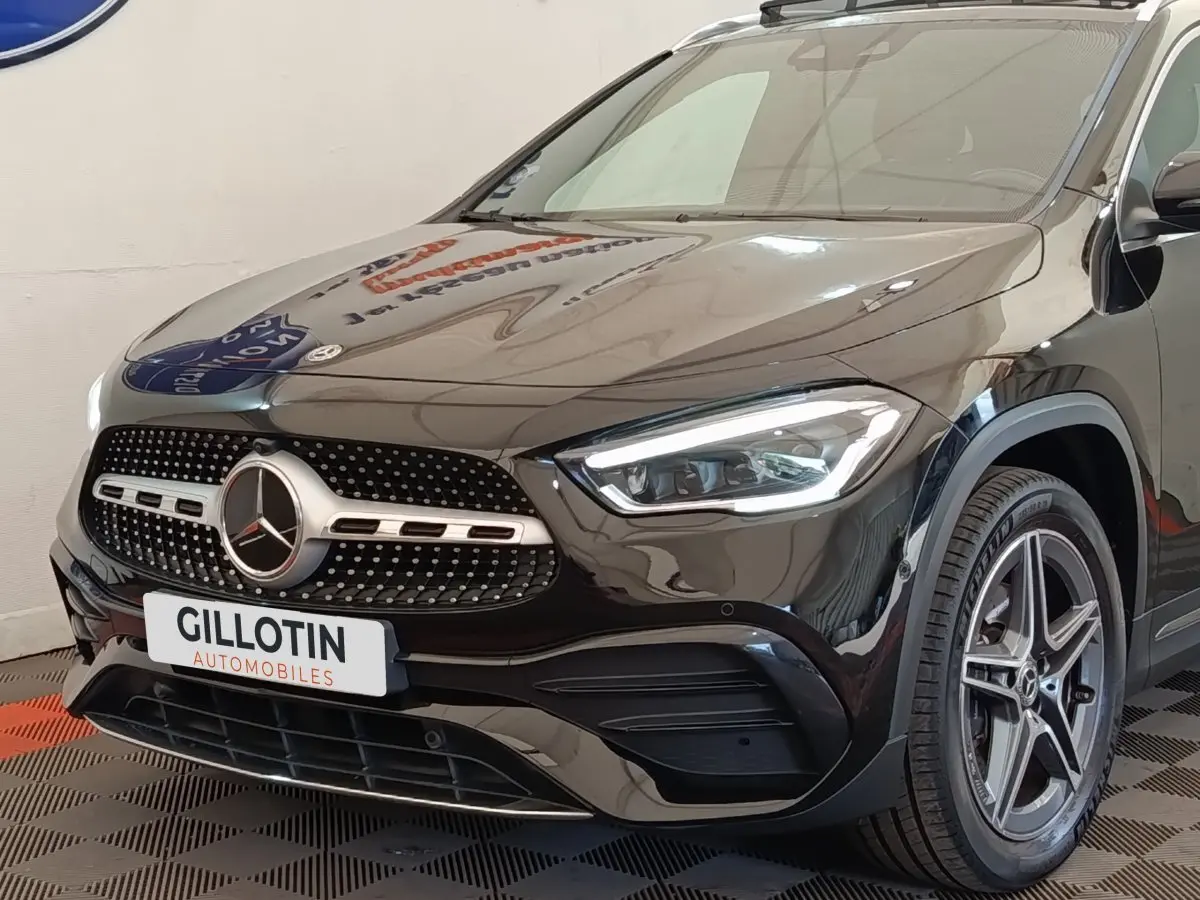 Vue 3/4 avant droite d'une Mercedes GLA 250 e AMG Line noire avec calandre étoile et phares LED allumés.