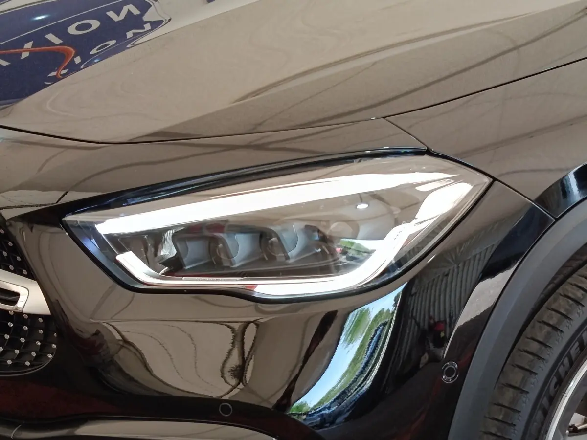 Gros plan sur le phare avant droit LED d’une Mercedes GLA 250 e AMG Line noire, avec partie de la calandre visible.