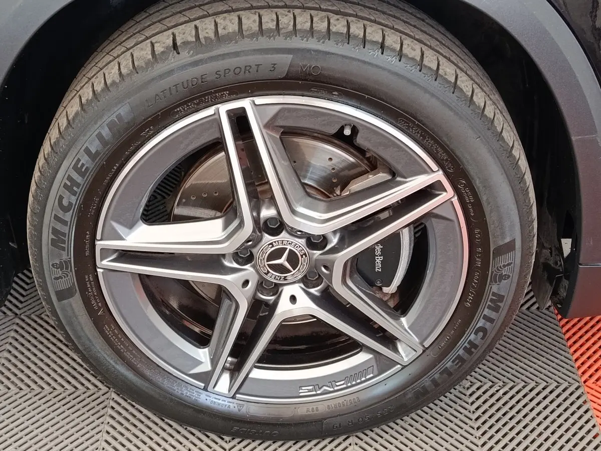 Gros plan sur la roue avant droite noire d’un Mercedes GLA 250 e AMG Line avec jante AMG étoile grise.