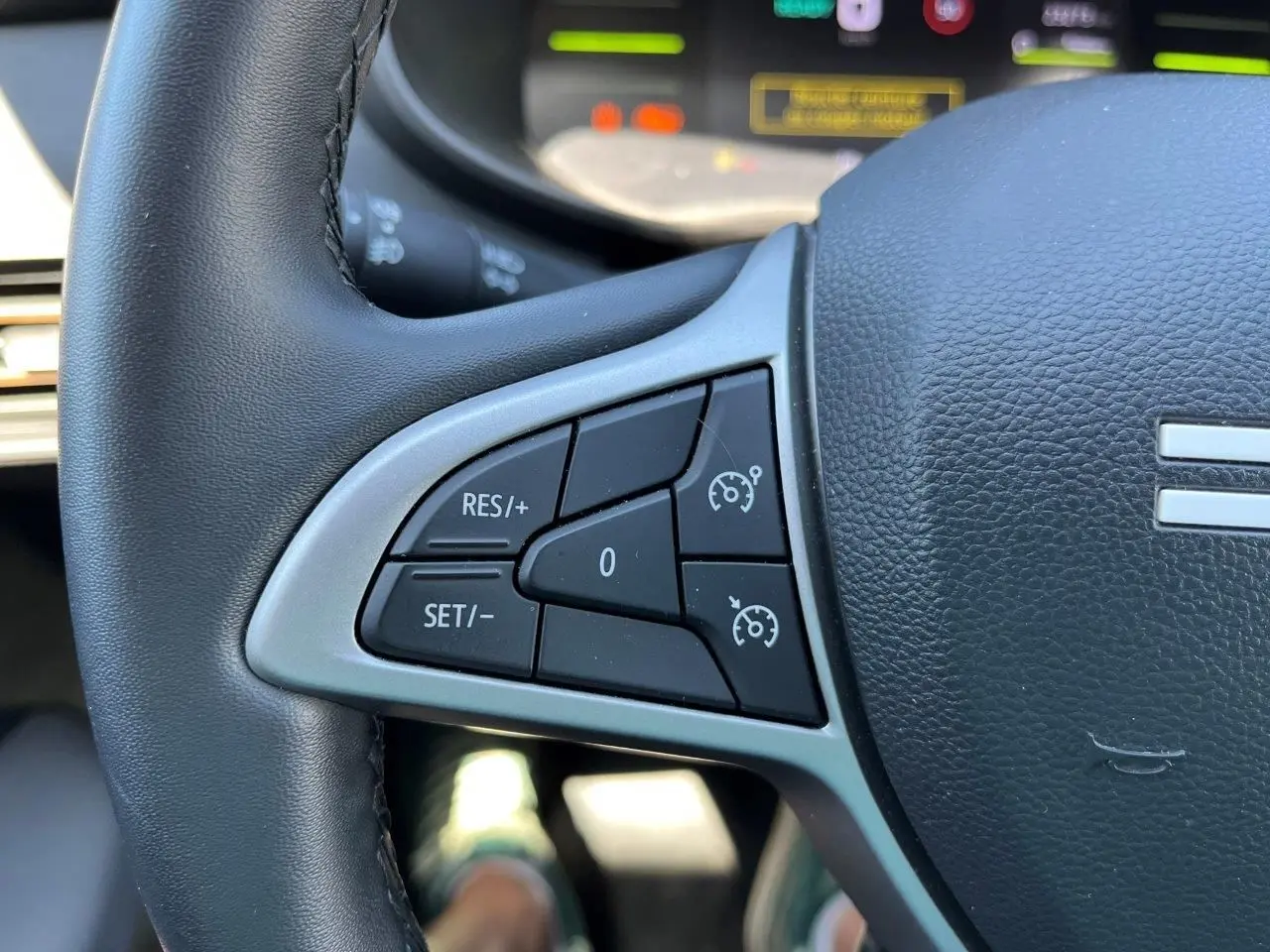Gros plan sur les commandes de régulateur de vitesse au volant noir du Dacia Jogger 1.6 Hybrid gris schiste, version 2025.