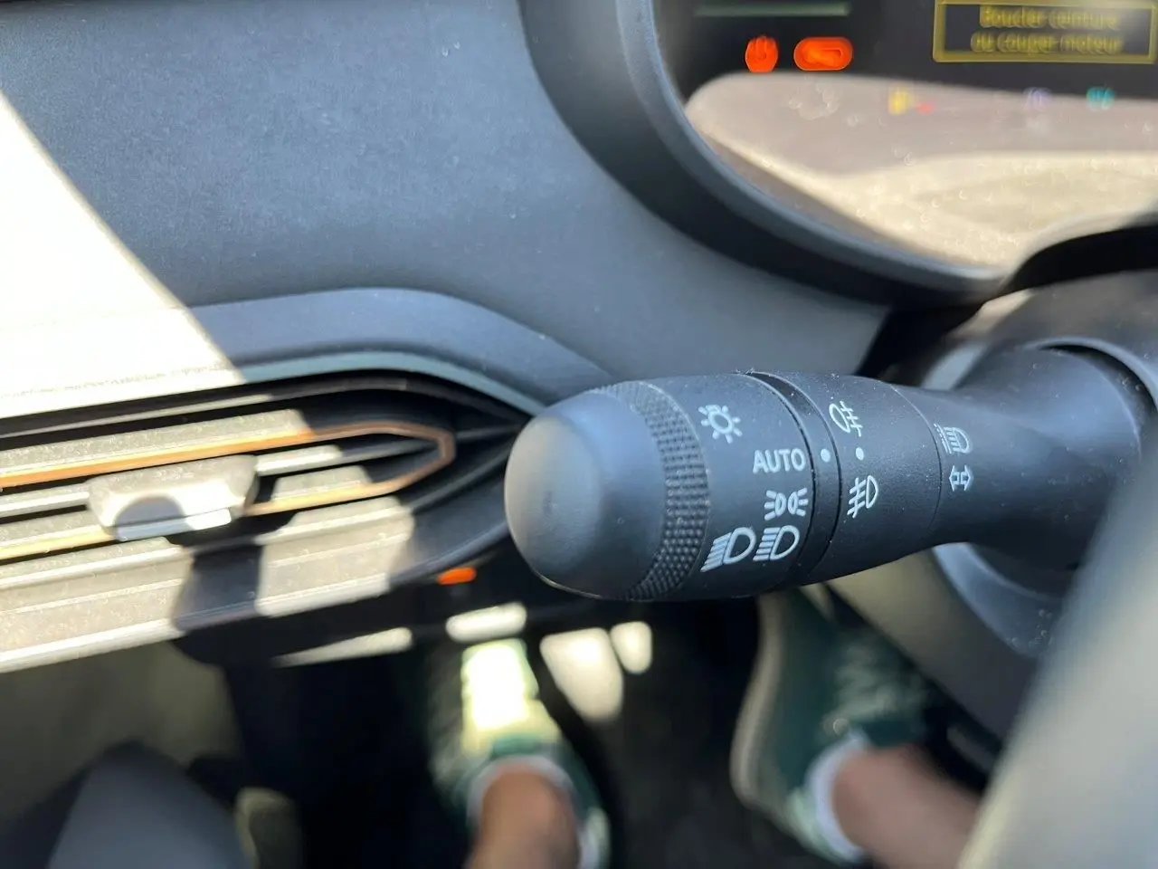 Gros plan sur la commande des phares du tableau de bord d’un Dacia Jogger gris schiste, intérieur lumineux.