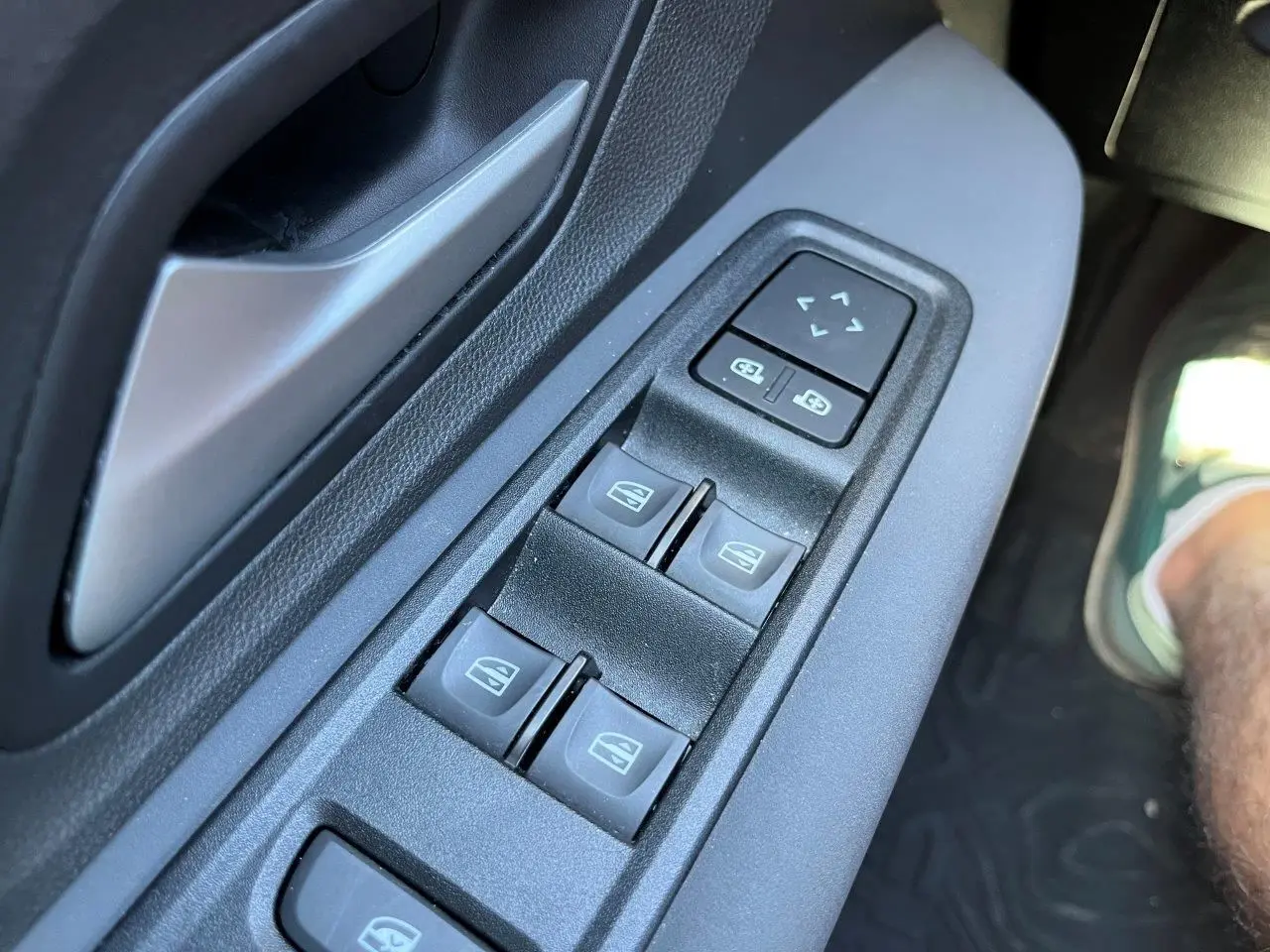 Gros plan sur les commandes des vitres électriques côté conducteur du Dacia Jogger gris schiste 2025, version hybride.