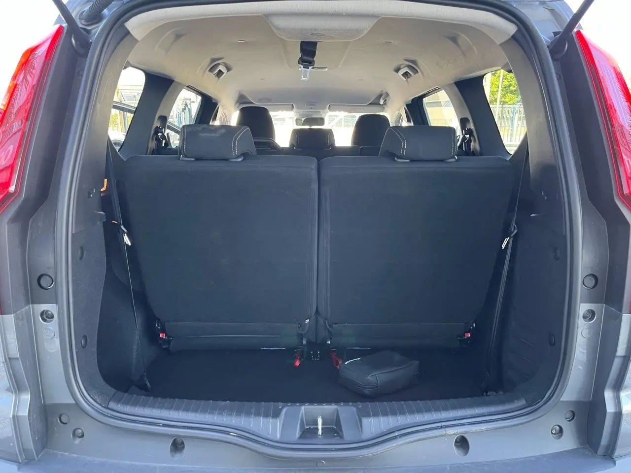 Vue arrière du coffre ouvert du Dacia Jogger gris schiste 2025, montrant les sièges arrière relevés et l’habitacle lumineux.