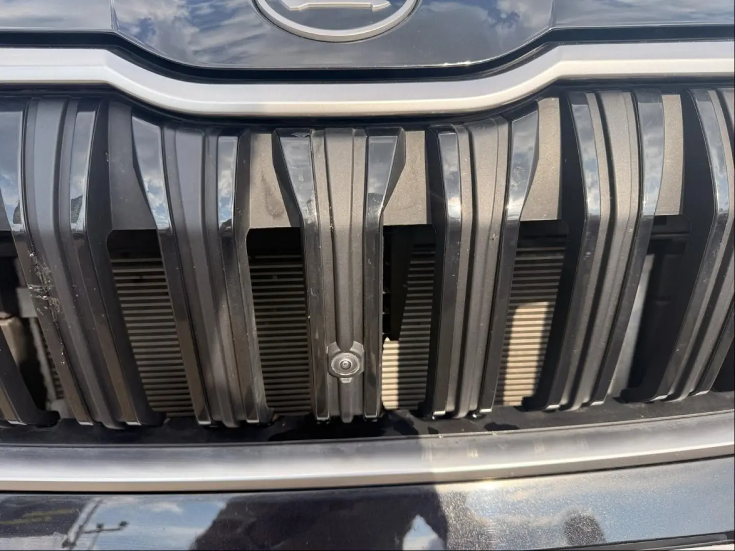 Gros plan sur la calandre noire verticale du Skoda Kodiaq 2024 avec capteur de stationnement intégré.