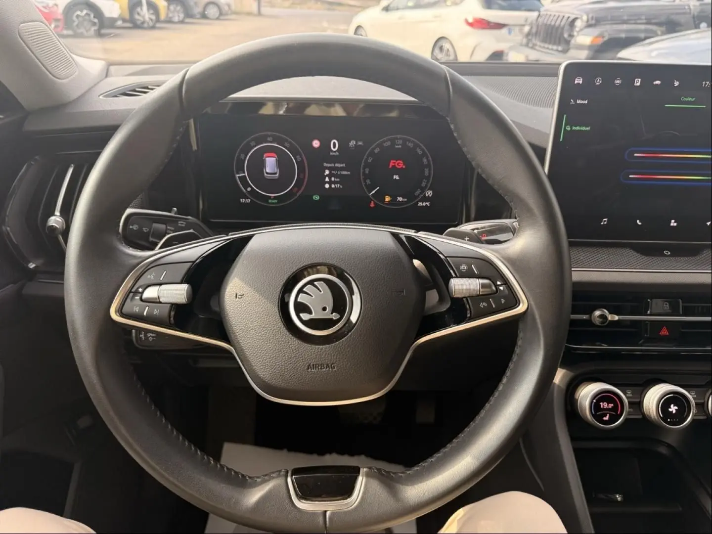 Vue intérieure centrée sur le volant noir du Skoda Kodiaq 2024 avec tableau de bord numérique et écran tactile.