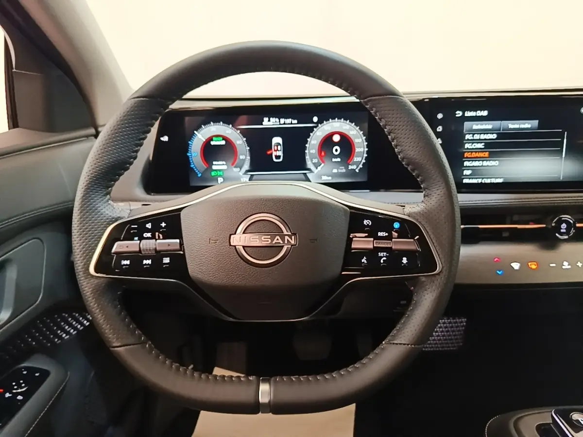 Vue frontale du volant cuir noir multifonctions de la Nissan Ariya 63kWh avec tableau de bord numérique et écran tactile.