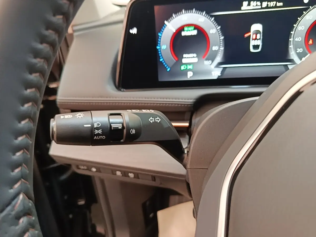 Gros plan sur la manette de clignotant côté gauche du tableau de bord du Nissan Ariya noir avec écran numérique visible.