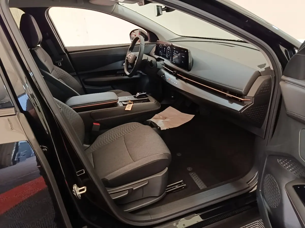 Vue intérieure côté conducteur du Nissan Ariya noir 2026, mettant en valeur le tableau de bord moderne et le volant cuir multifonctions.