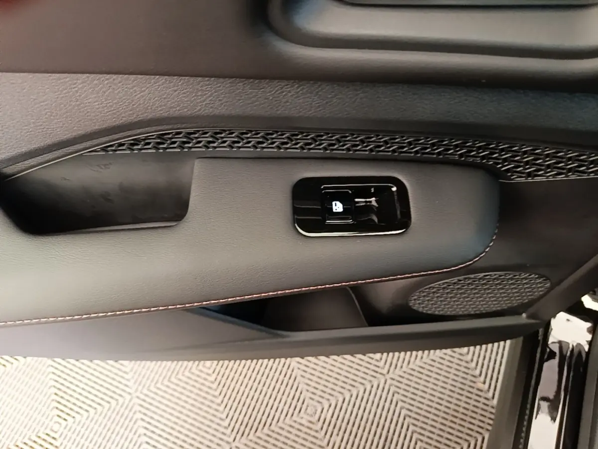 Gros plan sur la porte avant droite noire du Nissan Ariya 63kWh avec bouton de verrouillage et haut-parleur intégré.