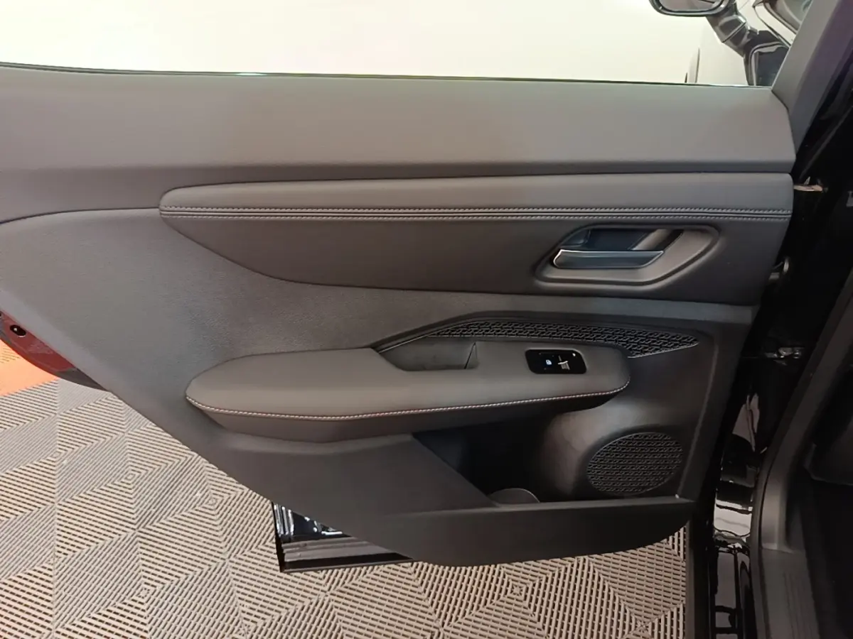 Vue intérieure de la porte arrière droite noire du Nissan Ariya 63kWh avec garniture cuir et commandes électriques.