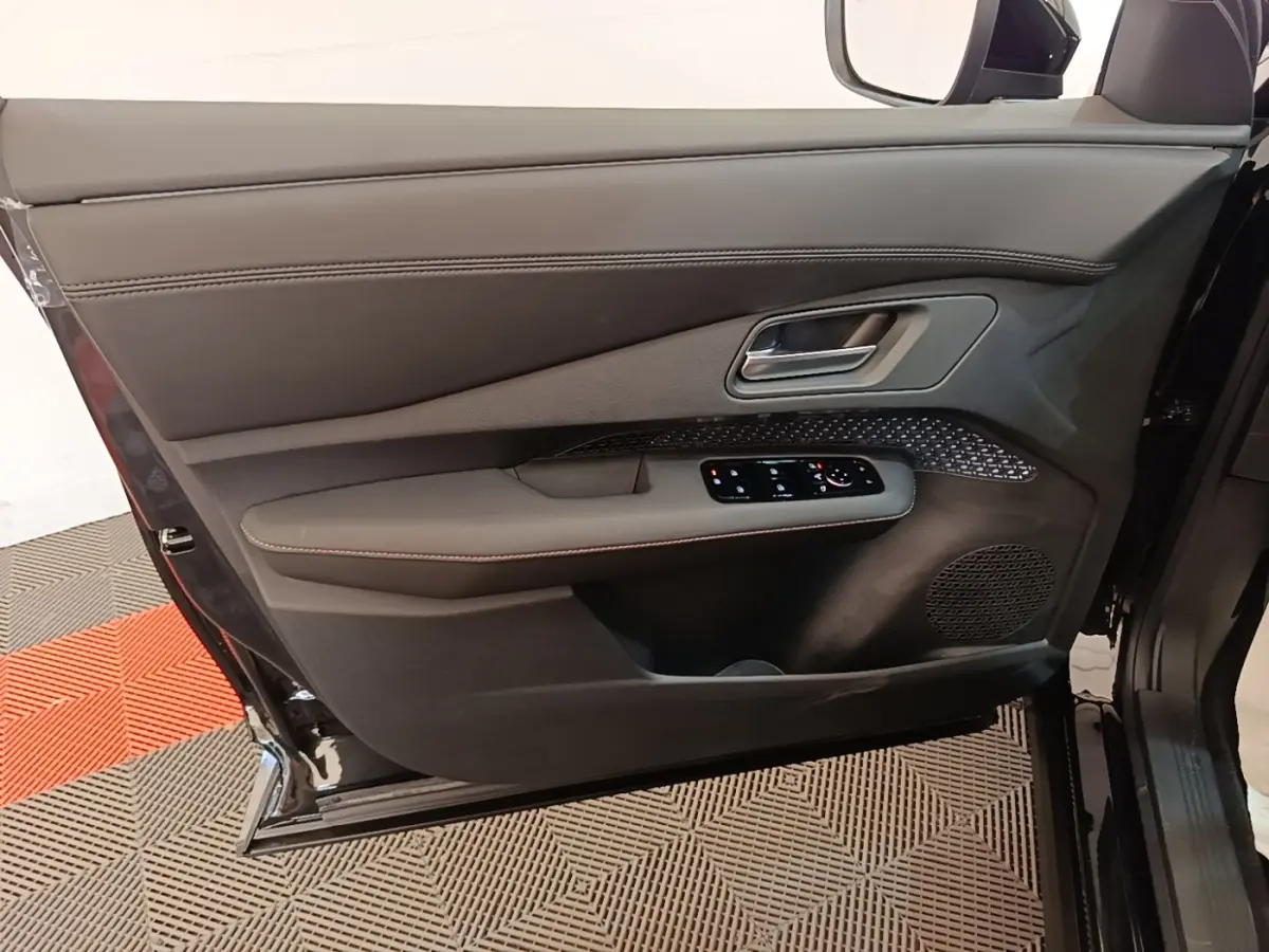 Vue rapprochée de la porte avant gauche noire du Nissan Ariya 63kWh 218ch Engage avec commandes électriques et haut-parleur intégré.