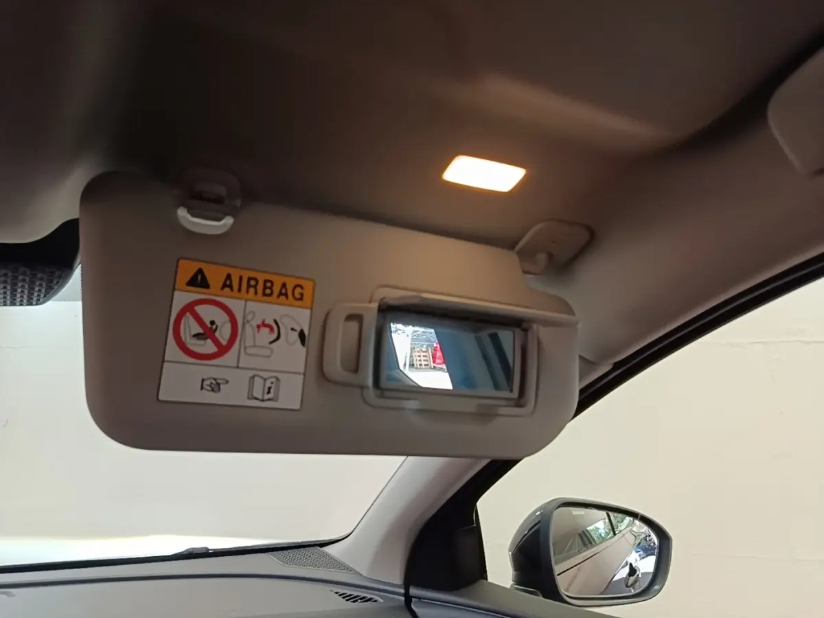 Détail intérieur du pare-soleil côté conducteur avec miroir et éclairage allumé dans un Nissan Ariya noir.