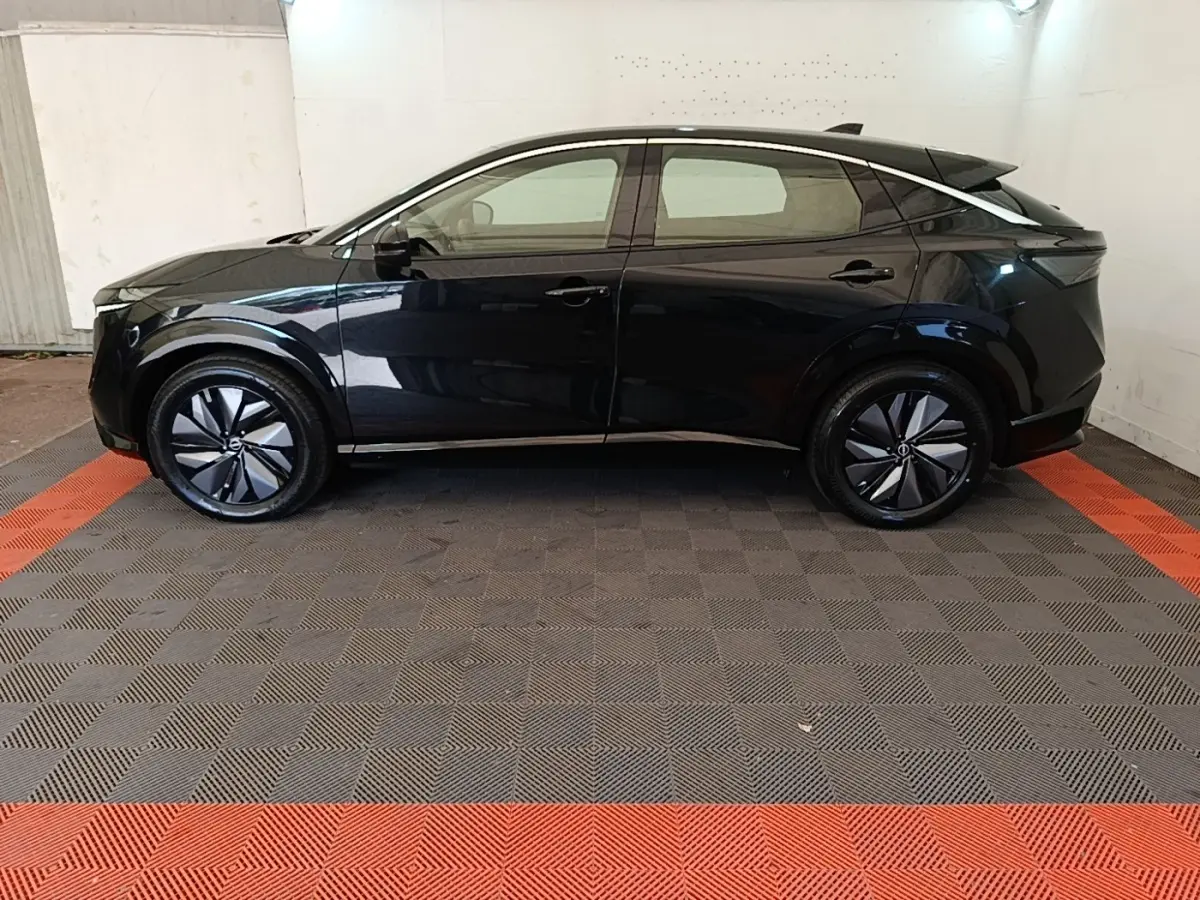 Vue de profil côté gauche du Nissan Ariya noir 63kWh 218ch Engage avec jantes stylisées et lignes épurées.