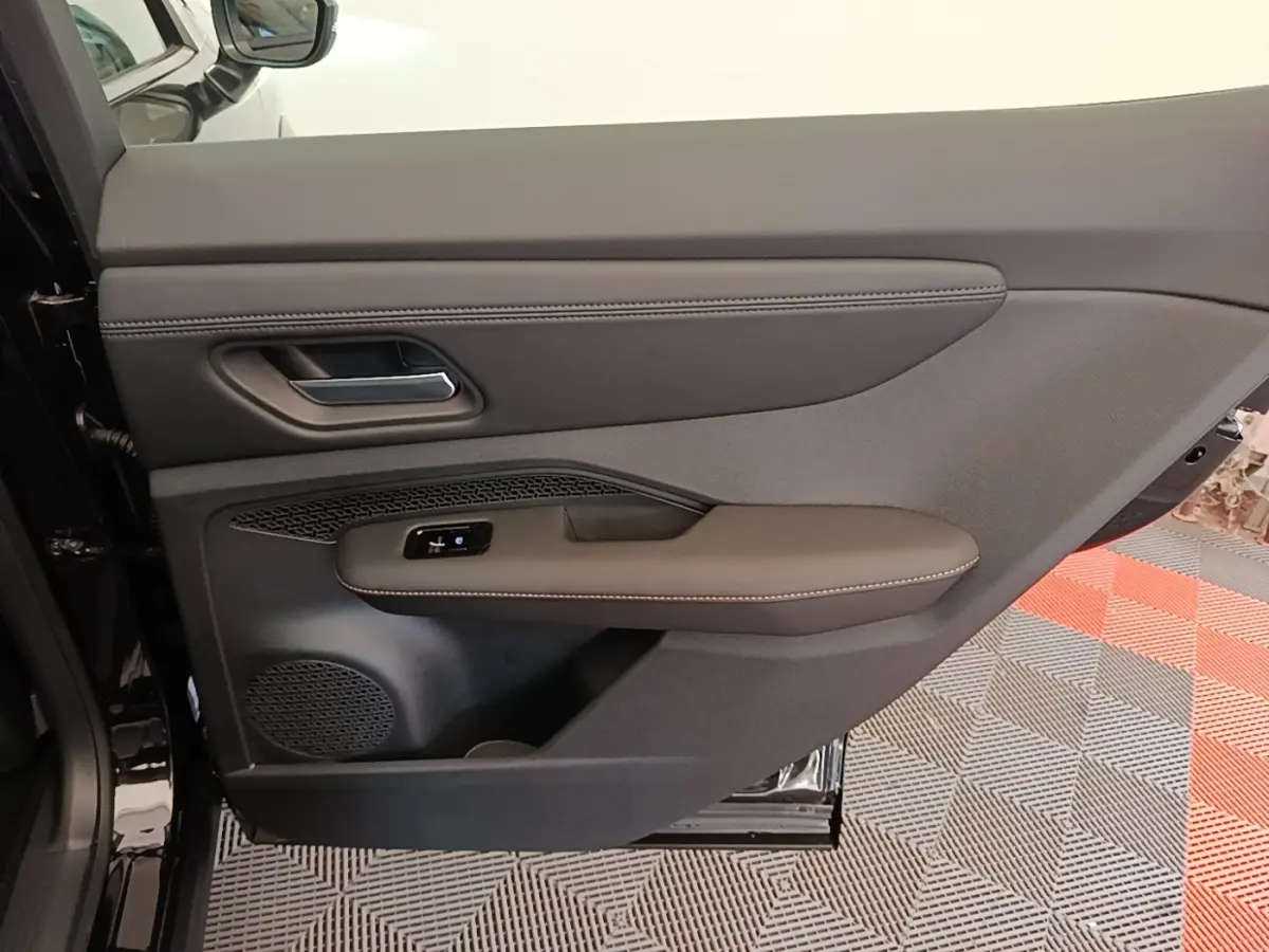 Porte intérieure côté gauche du Nissan Ariya noir 2026, avec garniture cuir et commandes électriques.