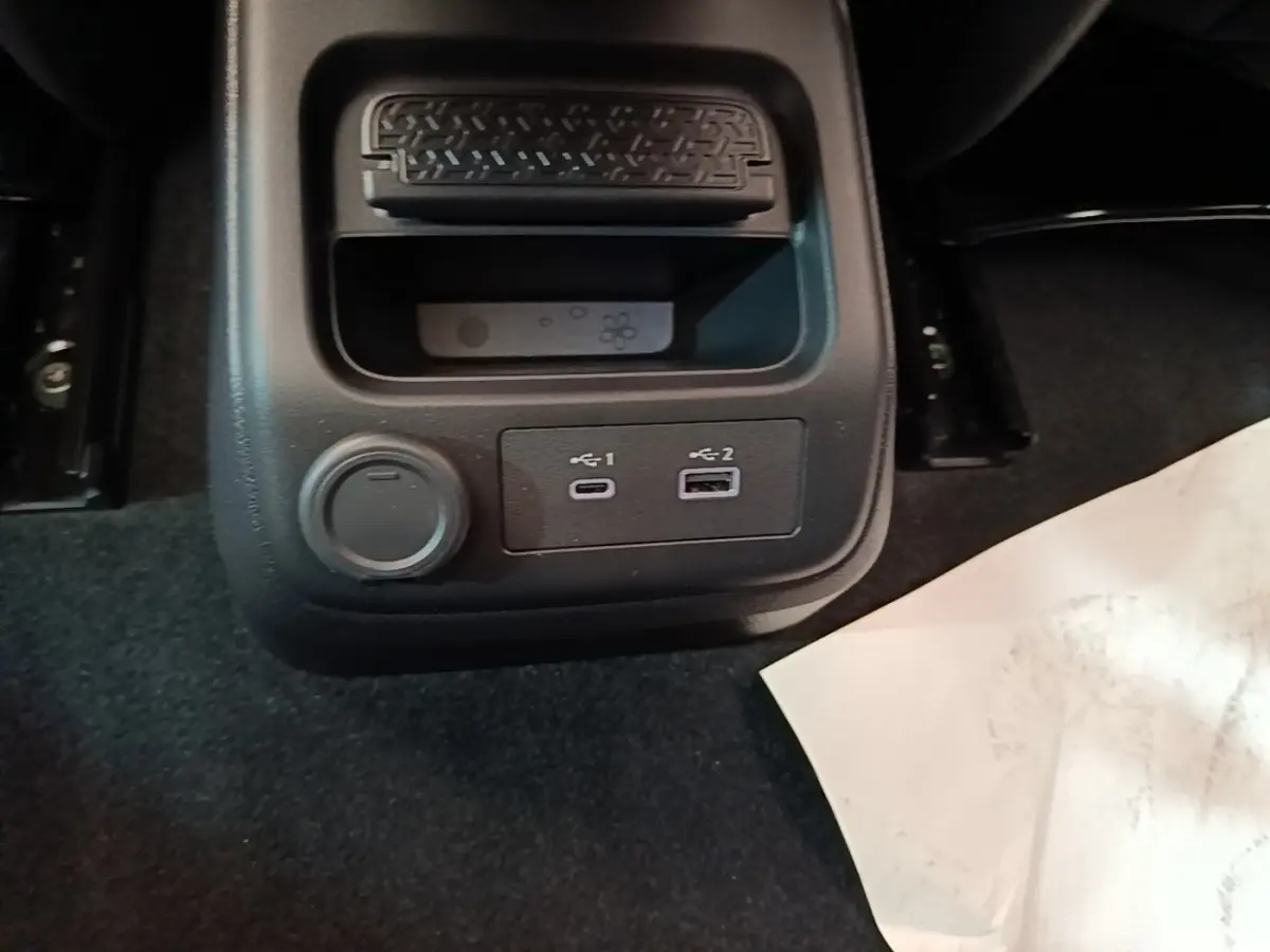 Gros plan sur la console centrale arrière noire du Nissan Ariya avec prises USB-C et USB-A, et prise 12V.
