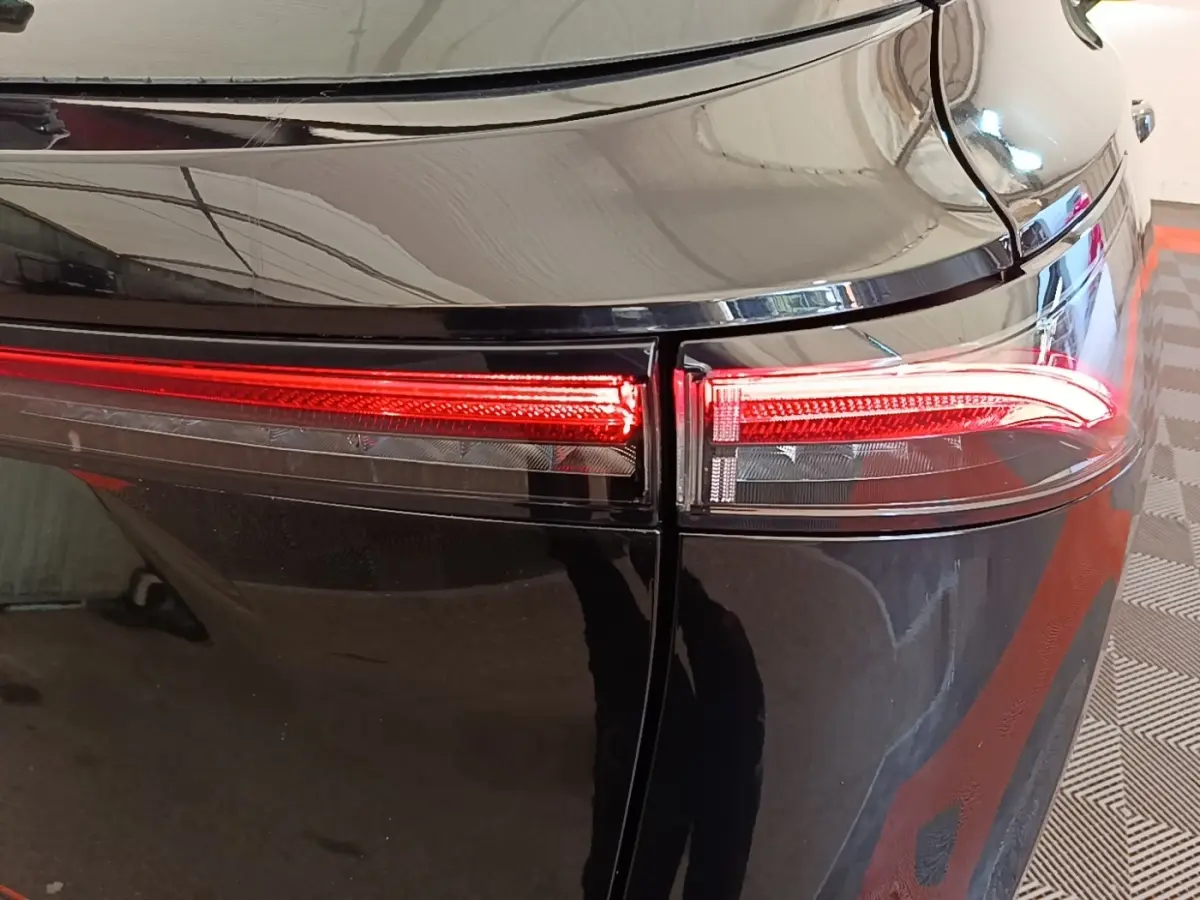 Gros plan sur le feu arrière droit rouge du Nissan Ariya noir, soulignant la finition lisse et brillante.