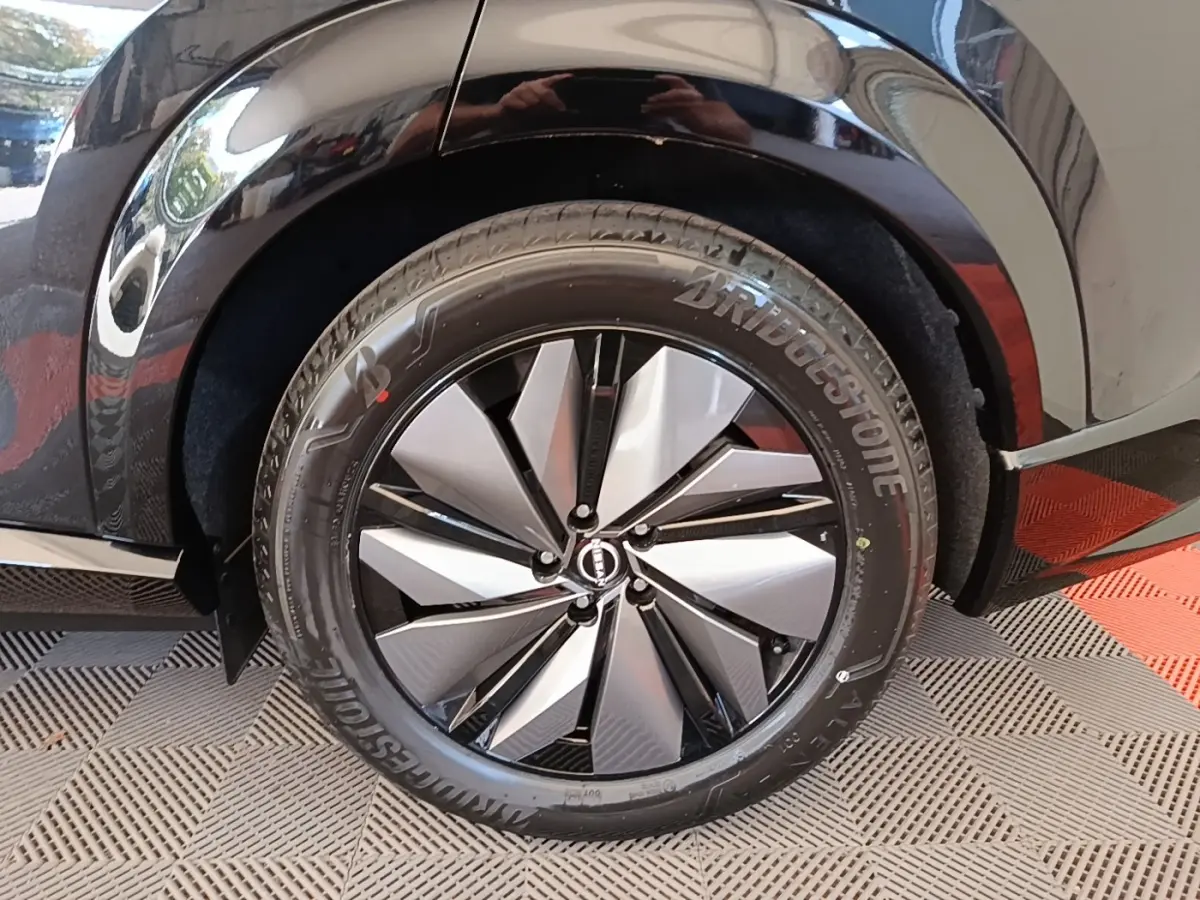 Gros plan sur la roue arrière droite noire du Nissan Ariya 63kWh avec jante argent et noire au design géométrique.
