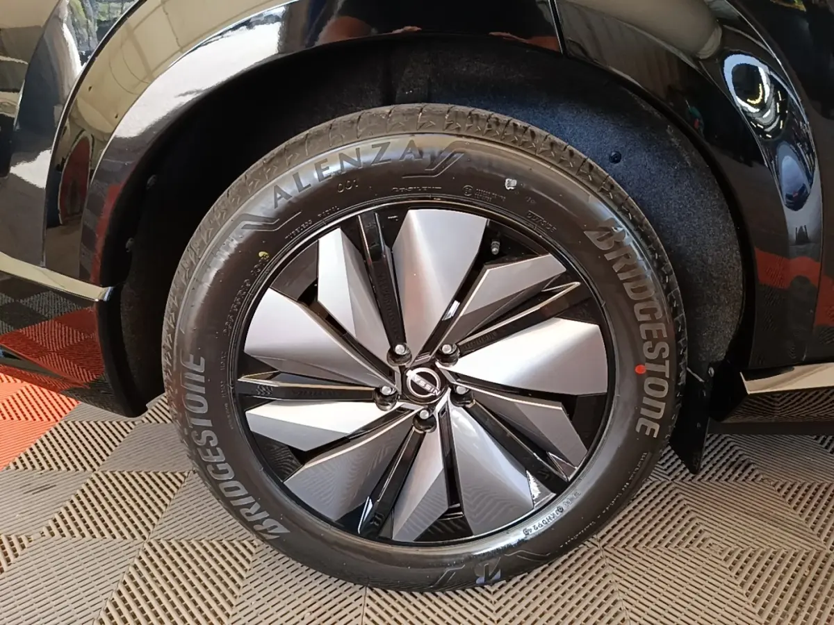 Gros plan sur la roue avant droite noire d’un Nissan Ariya 63kWh 218ch Engage avec jante alu bicolore.