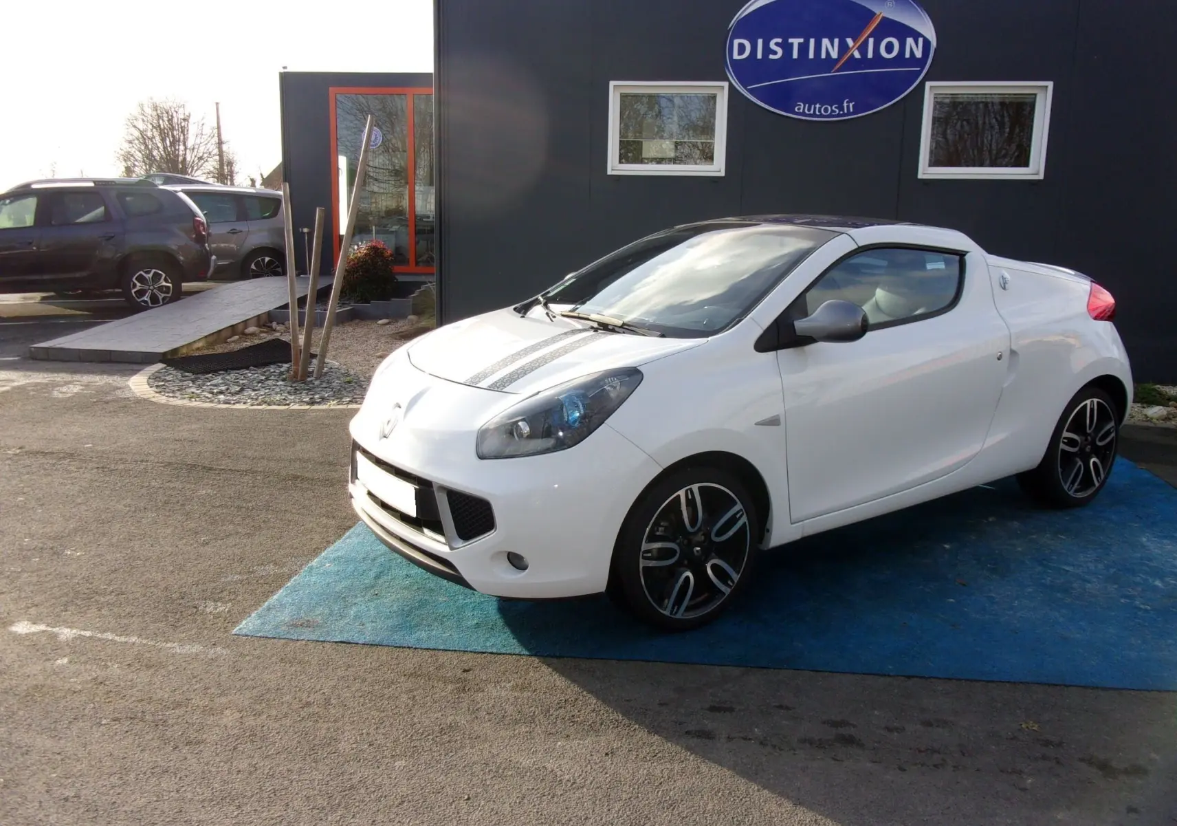 Renault Wind blanc glacier en 3/4 avant droit, avec bandes noires sur le capot et jantes alliage noires.