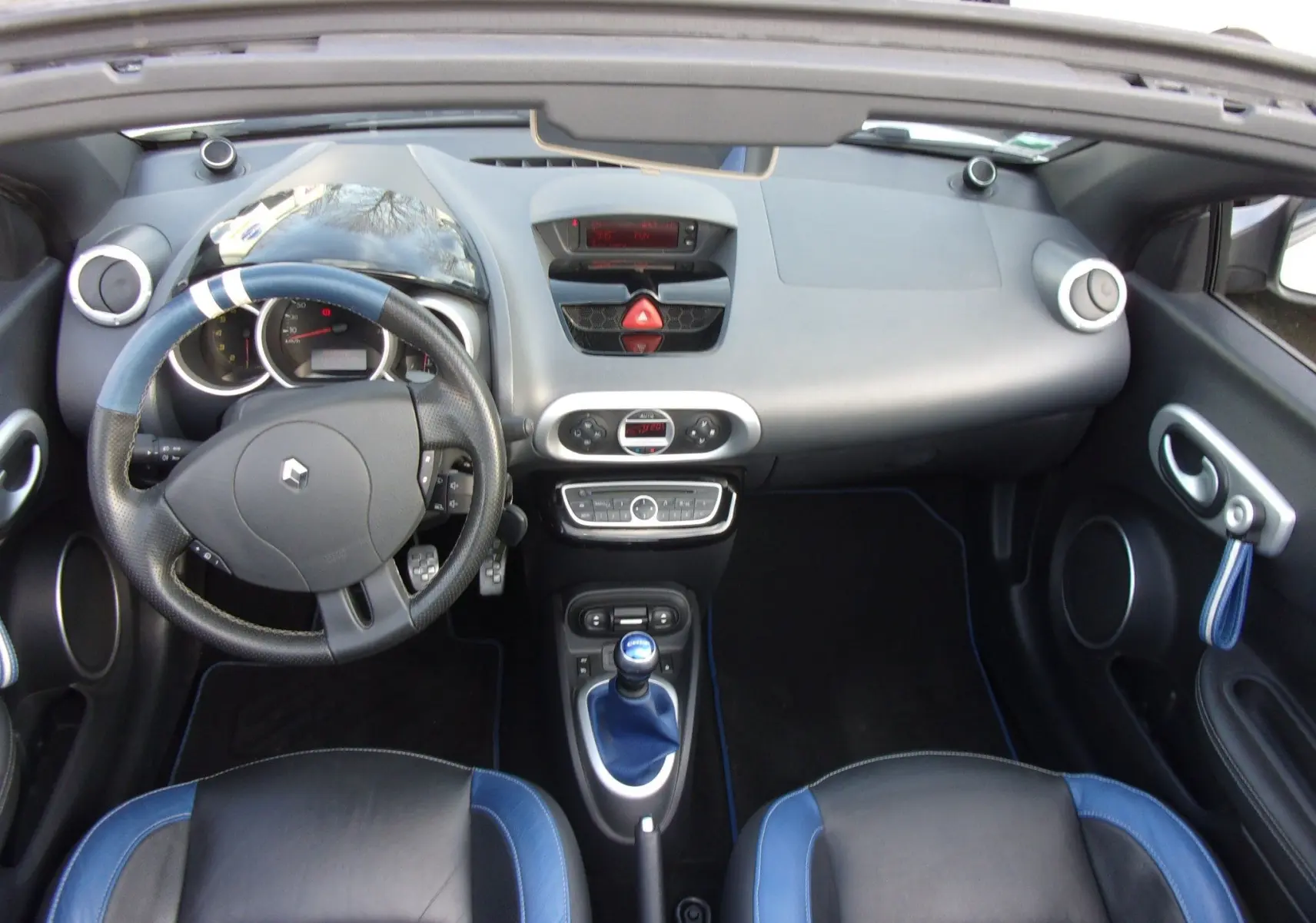 Vue intérieure du tableau de bord et volant de la Renault Wind 1.6 16V 133 Gordini avec sièges cuir noir et bleu.
