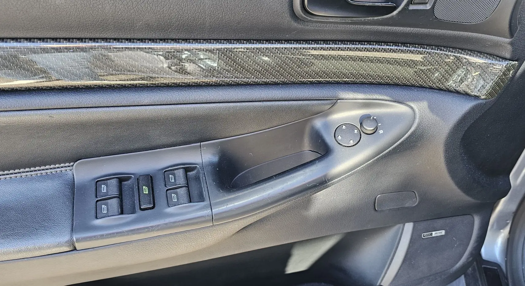 Gros plan sur la porte avant gauche de l'Audi RS4 Avant grise, montrant les commandes des vitres et le revêtement carbone.