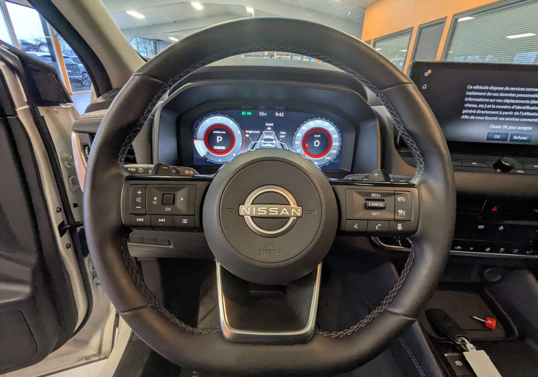 Vue centrée sur le volant du Nissan Qashqai 2024, tableau de bord numérique et écran tactile visibles, intérieur noir.