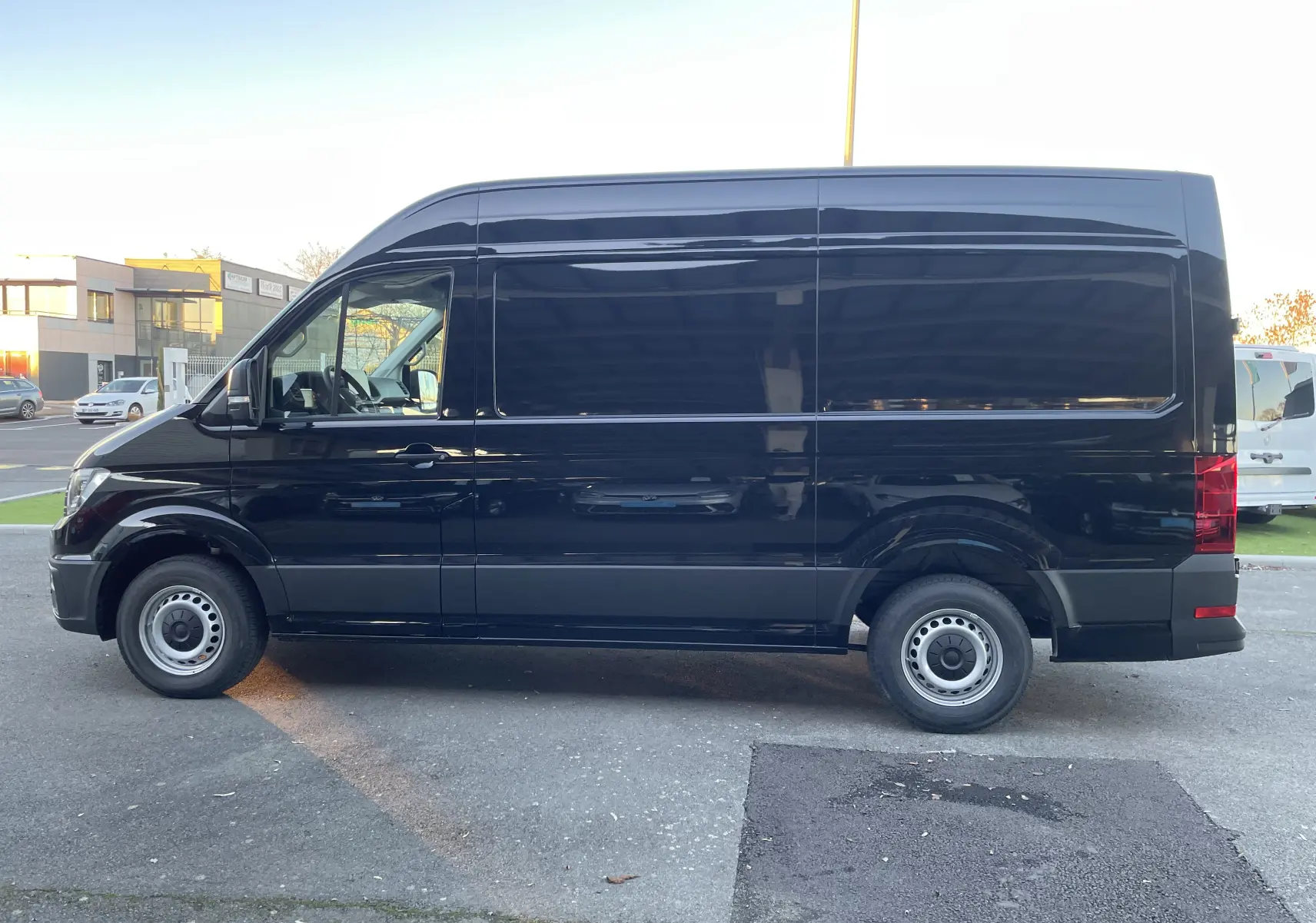 Profil latéral gauche d'un Volkswagen Crafter Van noir intense 2025, version longue et haute, sans fenêtres latérales arrière.