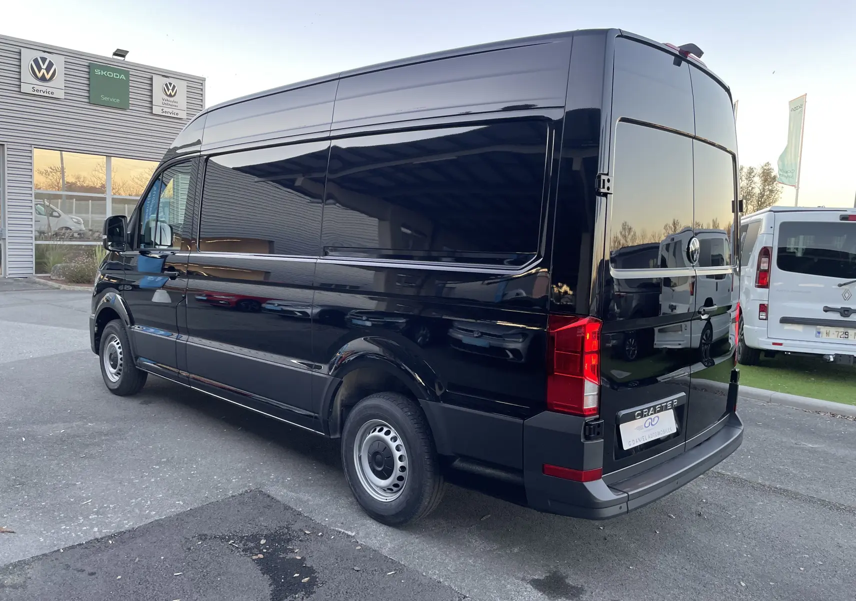 Vue 3/4 arrière côté droit d'un Volkswagen Crafter Van noir intense, avec vitres arrière teintées et feux LED visibles.