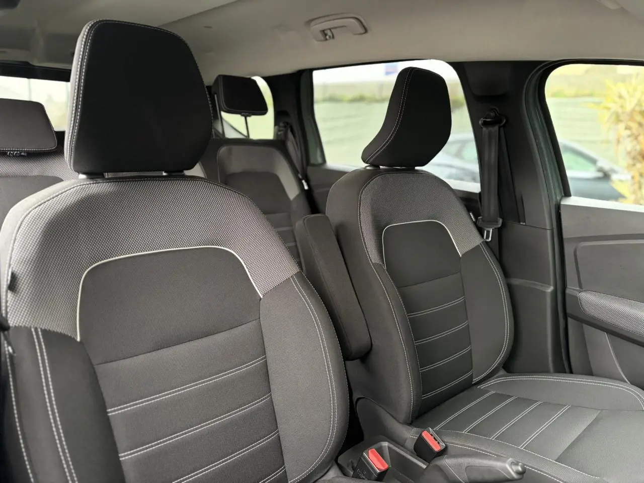 Vue intérieure rapprochée des sièges avant noirs avec surpiqûres blanches du Dacia Jogger 2025, finition Expression.