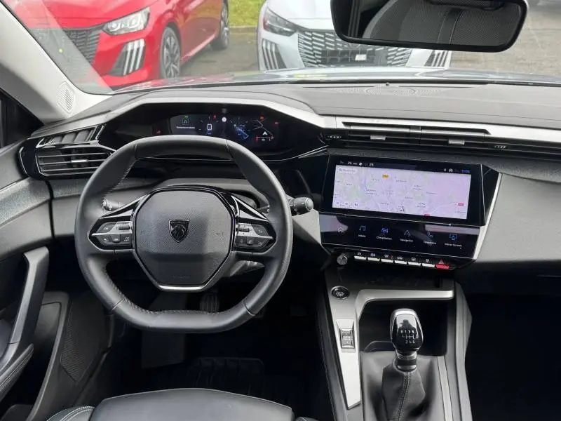 Vue intérieure du poste de conduite du Peugeot 308 2024 Gris Artense, avec volant compact et écran tactile central affichant la navigation.