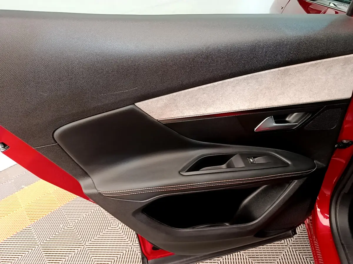 Vue rapprochée de la porte avant gauche rouge du Peugeot 3008 GT 2021, avec garniture noire et poignée argentée.