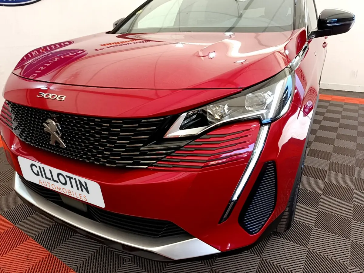 Vue avant droite rapprochée du Peugeot 3008 rouge avec calandre noire et feux LED distinctifs en forme de griffes.