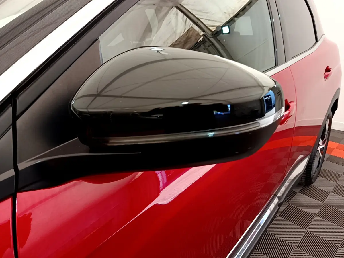 Gros plan sur le rétroviseur noir côté gauche du Peugeot 3008 rouge, avec partie latérale visible en arrière-plan.
