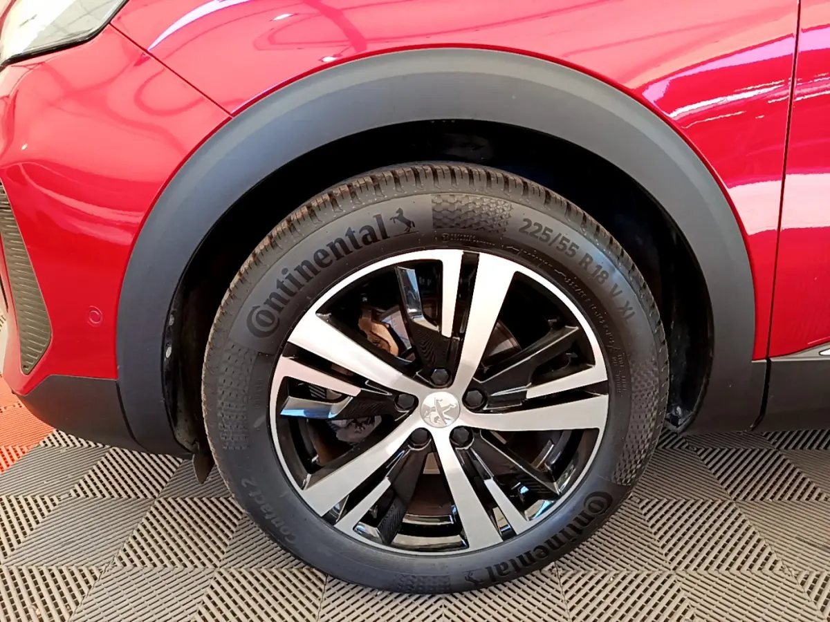 Gros plan sur la roue avant gauche d’un Peugeot 3008 GT rouge avec jante alliage bicolore et pneu Continental.