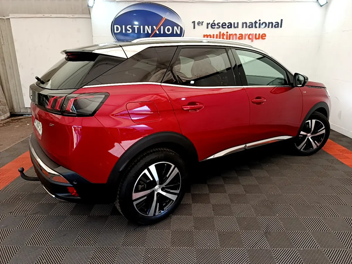 Vue 3/4 arrière droite d’un Peugeot 3008 GT rouge avec toit noir et jantes alliage bicolores.