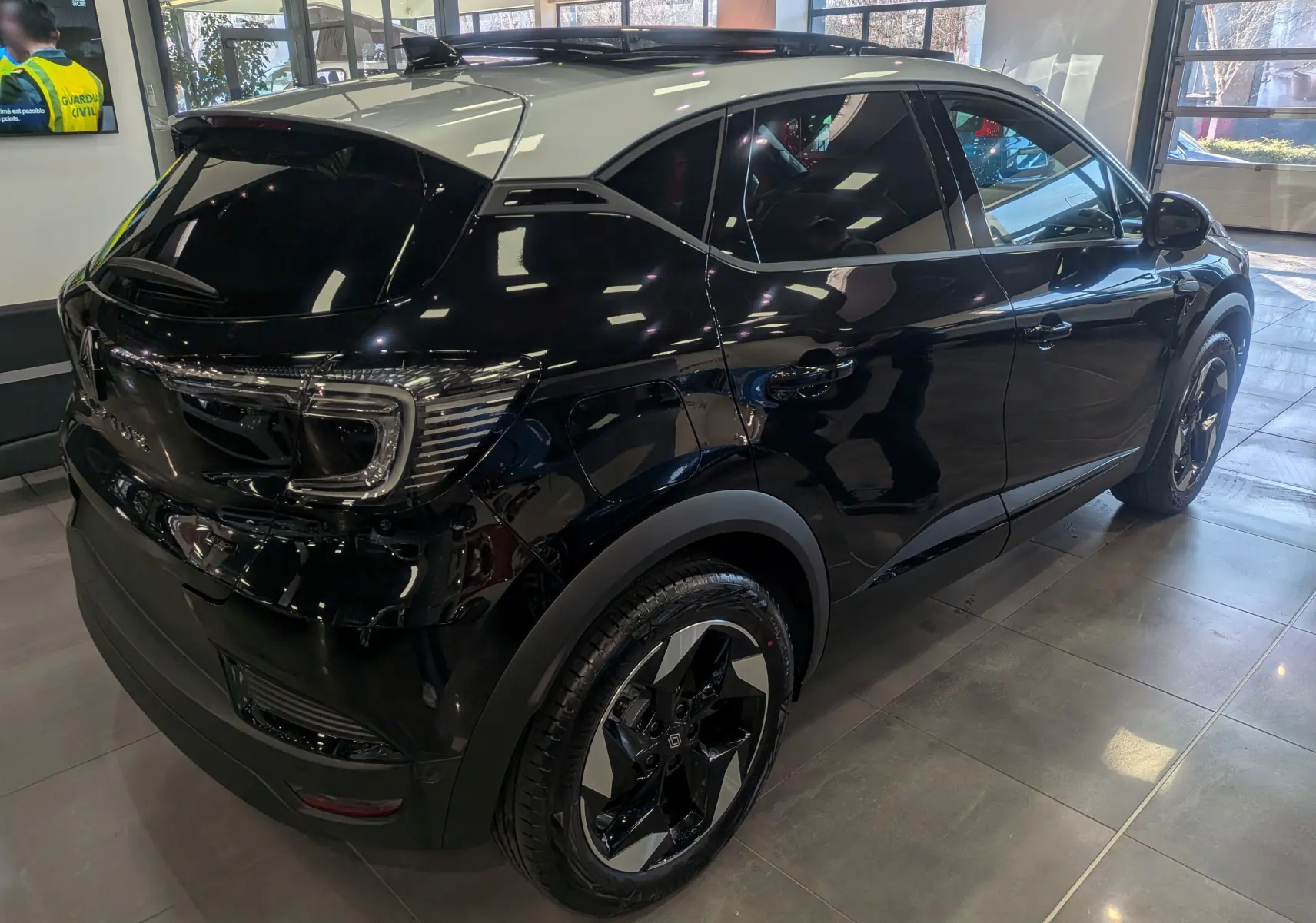 Vue 3/4 arrière droite du Renault Captur E-TECH noir avec toit gris Highland, roues biton et feux arrière LED distinctifs.