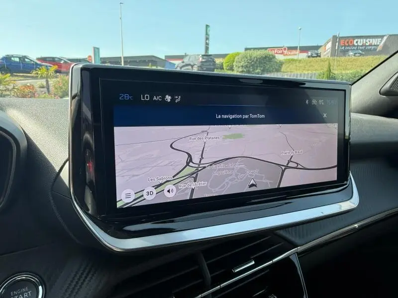 Vue intérieure du tableau de bord du Peugeot 2008 2025, écran tactile de navigation TomTom en fonctionnement.
