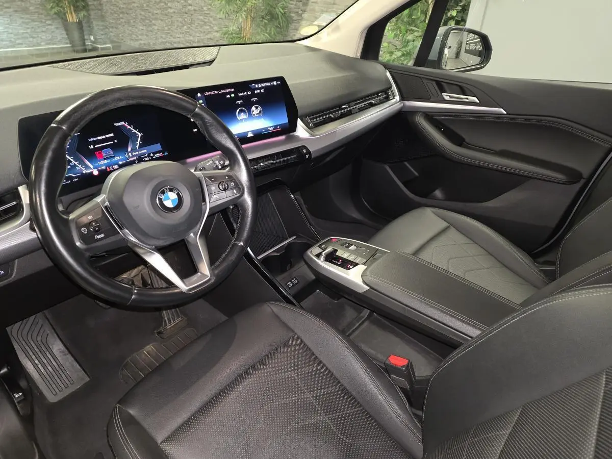 Intérieur noir de BMW Série 2 218d Active Tourer 2023, vue côté conducteur sur tableau de bord et volant cuir multifonctions.