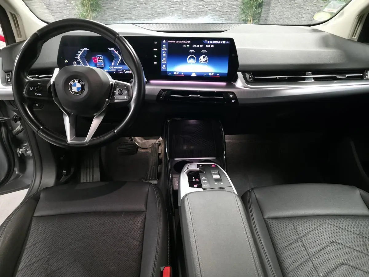 Intérieur BMW Série 2 218d gris, vue avant centrée sur tableau de bord numérique et console centrale moderne.