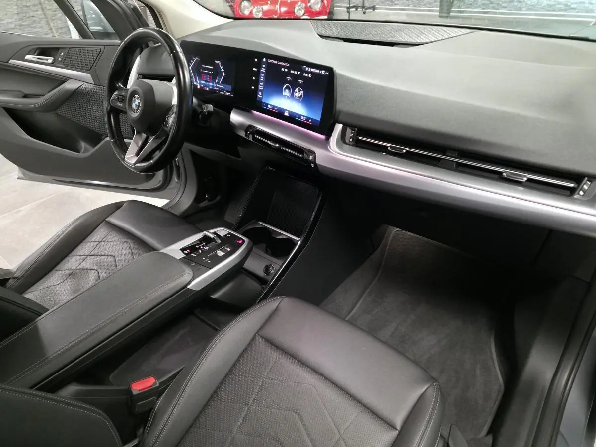 Intérieur avant de la BMW Série 2 218d gris, vue côté conducteur avec tableau de bord numérique et sellerie noire.