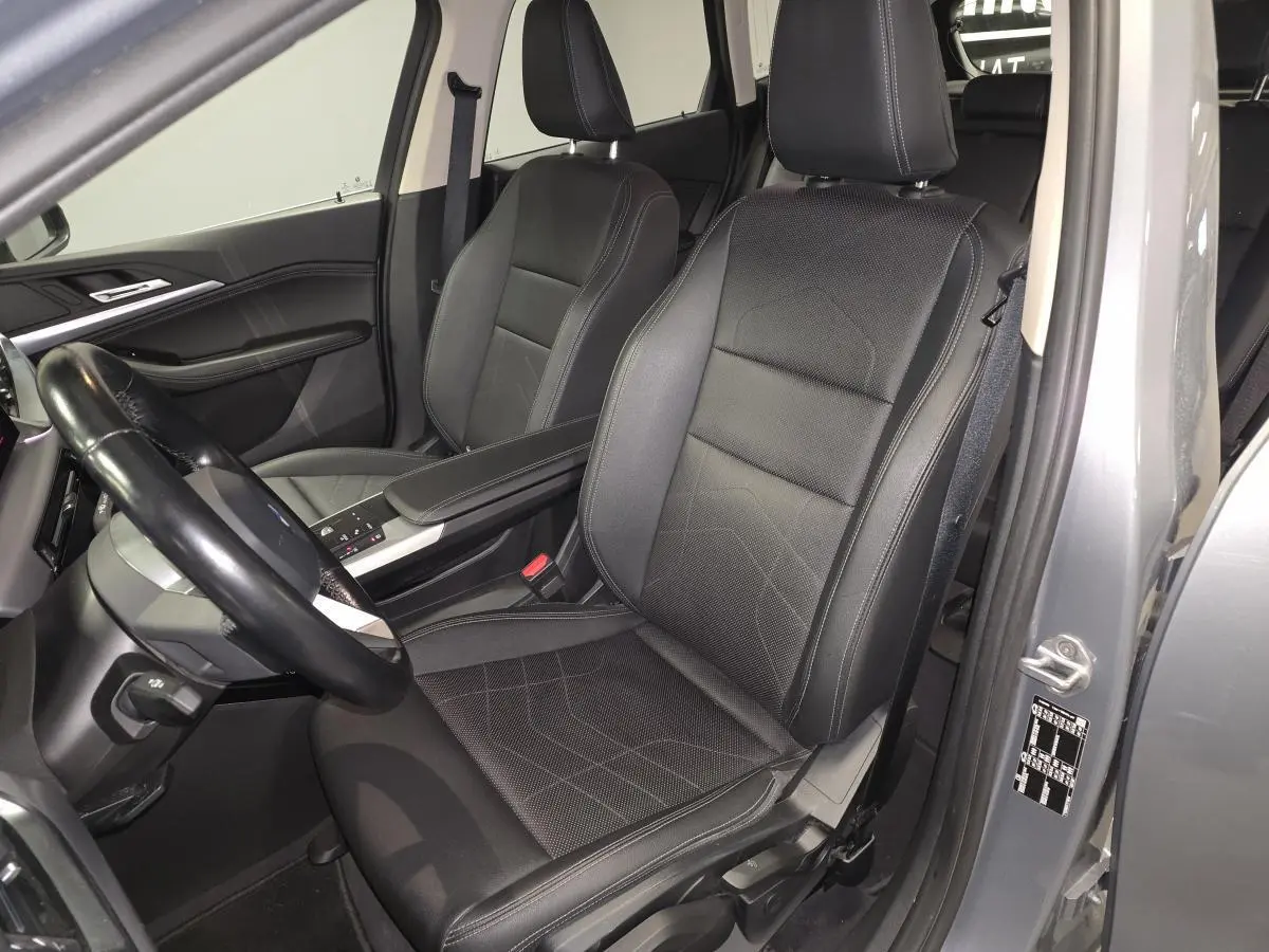 Vue intérieure côté conducteur de la BMW Série 2 218d gris, sièges en similicuir noir avec accoudoir central.